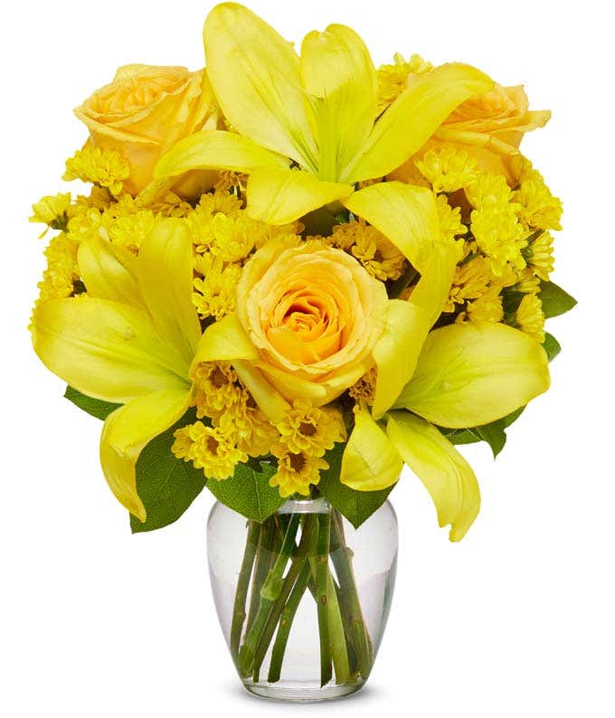 A bouquet featuring yellow lilies, yellow roses, and yellow poms, with an optional glass vase.