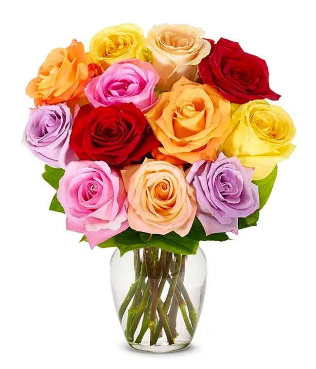 A bouquet of multicolored roses in a clear vase, featuring red, pink, orange, yellow, peach, and lavender blooms, arranged with green leaves for a vibrant and cheerful display.