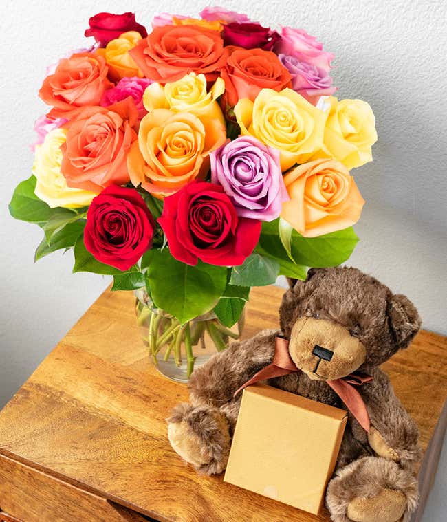 Two Dozen Assorted Rainbow Roses with Chocolates &amp; Teddy Bear in a Clear Glass Vase