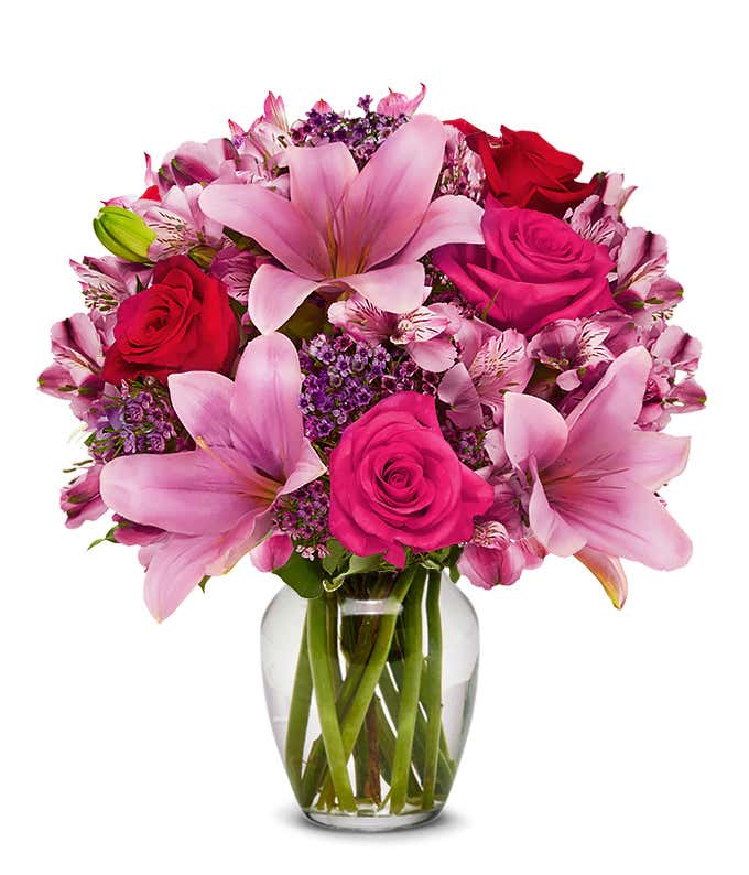 A beautiful arrangement featuring pink Asiatic lilies, pink and red roses, and alstroemeria, optionally arranged in a glass vase. This elegant mix offers a lovely and vibrant display