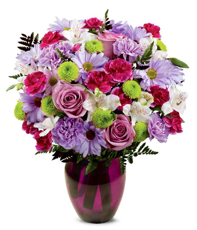 A bouquet featuring lavender daisies, lavender roses, hot pink mini carnations, lavender carnations, white alstroemeria, and green button poms, with an optional vase.