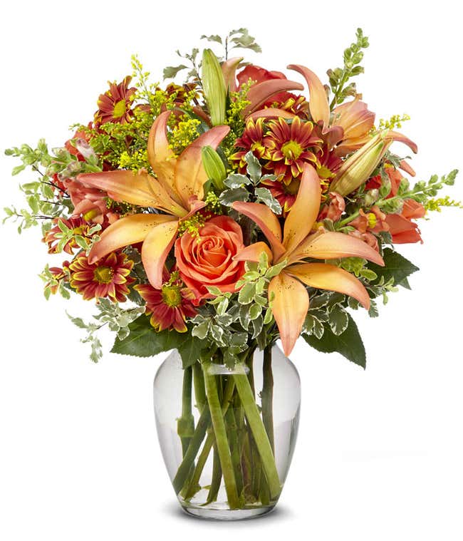 Bi-colored lilies, orange roses and Fall daisies in an orange vase for Fall