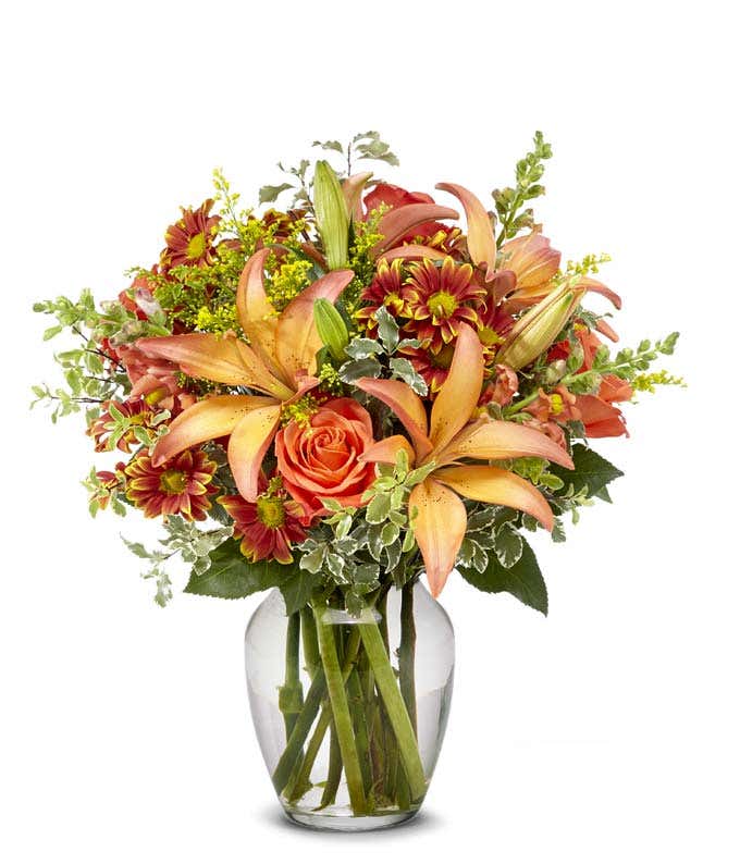 Bi-colored lilies, orange roses and Fall daisies in an orange vase for Fall