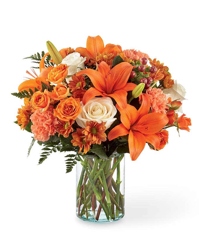 Orange lilies, cream roses and orange roses are arranged for Fall delivery