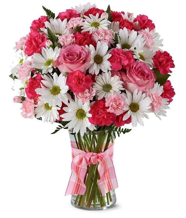 A delightful arrangement featuring hot pink spray roses, white traditional daisies, and pink mini carnations, beautifully arranged in a clear vase with a pink bow. This vibrant mix offers a cheerful and elegant display.