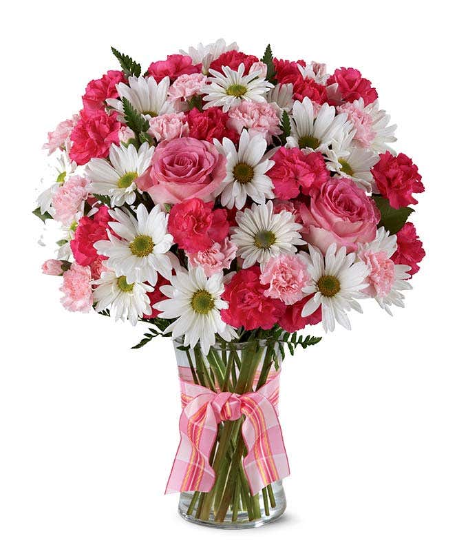 A delightful arrangement featuring hot pink spray roses, white traditional daisies, and pink mini carnations, beautifully arranged in a clear vase with a pink bow. This vibrant mix offers a cheerful and elegant display.