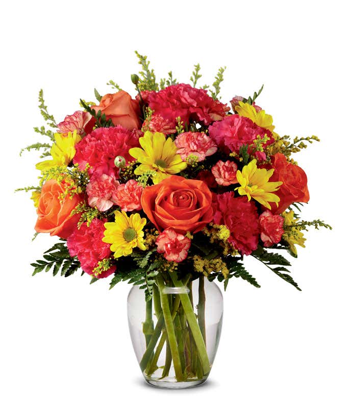 Orange roses, yellow daisies, with hot pink and orange carnations arranged into a clear glass vase