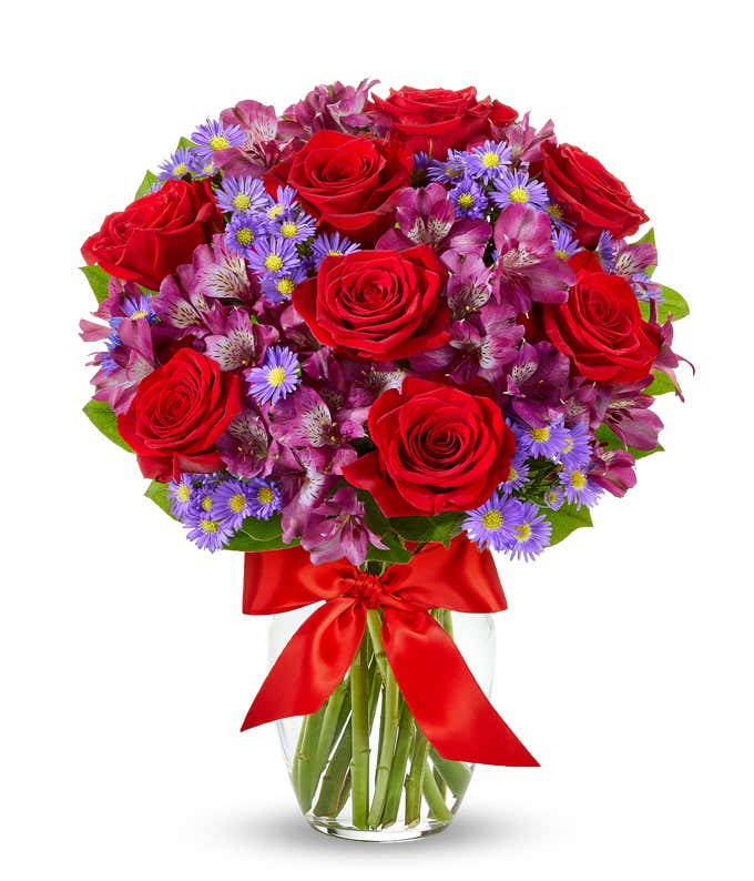 Red roses arranged with purple alstroemeria and monte casino. 