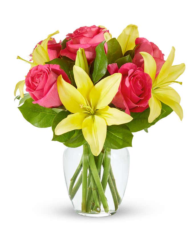 A beautiful arrangement featuring yellow lilies and pink roses, elegantly presented in a clear glass vase. This vibrant mix offers a cheerful and uplifting display, perfect for brightening any space.