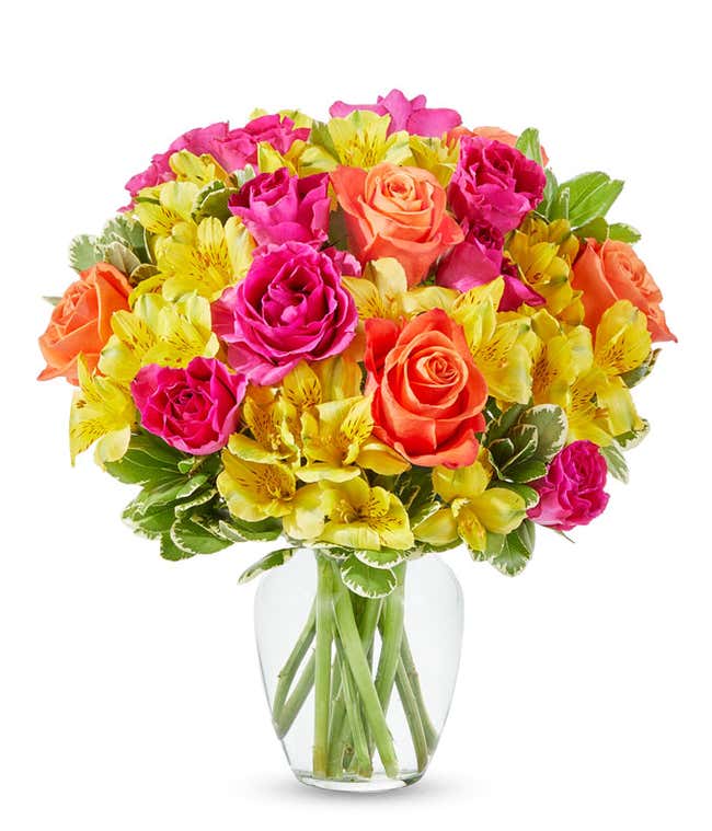 Orange roses, hot pink roses and yellow alstroemeria in glass vase