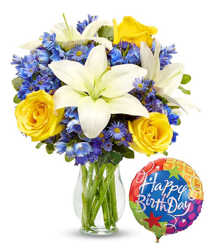 A cheerful birthday arrangement featuring a mylar balloon, white Asiatic lilies, yellow roses, blue delphinium, and purple Monte Casino. This vibrant mix of flowers brings a festive and celebratory touch to any birthday.