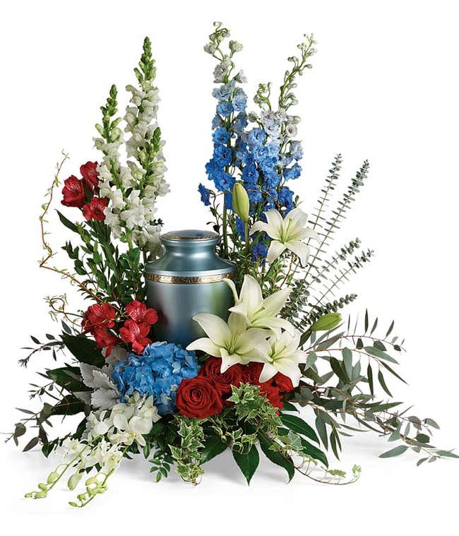 A patriotic Urn Bouquet with blue hydrangea &amp; delphinium, red roses, alstroemeria, carnations, and white asiatic lilies, snapdragons, and dendropium orchids