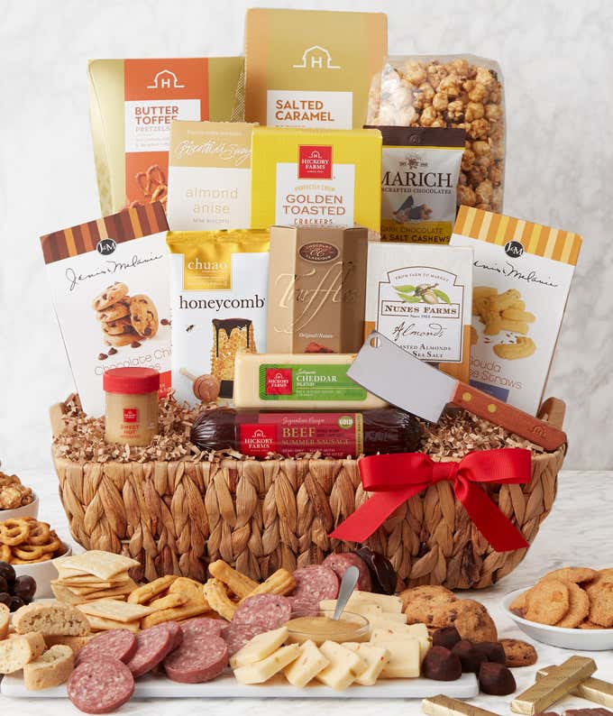 Woven gift basket with gourmet snacks: butter toffee pretzels, salted caramel popcorn, biscotti, toasted crackers, dark chocolate cashews, chocolate chip cookies, honeycomb chocolates, truffles, cheddar cheese, beef sausage, almonds, cheese straws, and a 