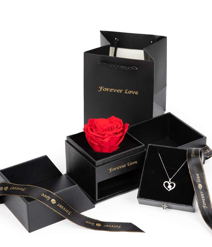 Gift set featuring a single red rose in a black box, a heart-shaped silver necklace in another box, black packaging with Forever Love written in gold, and a black ribbon with gold text