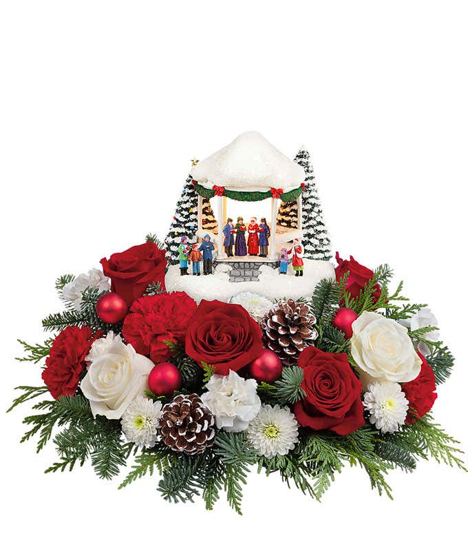 Red roses, white roses (available in Deluxe & Premium sizes), red carnations, white miniature carnations, white button chrysanthemums, cedar, noble fir, pinecone & red ornament details, all complemented by a keepsake Thomas Kinkade figurine