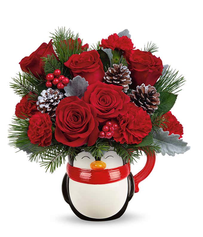 A festive arrangement with red roses, red carnations, floral greens, berries, and pinecone picks.