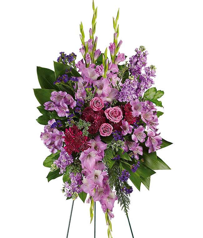 A stunning standing funeral spray featuring purple spray roses, purple alstroemeria, purple gladiolus, purple cushion mums, and sinuata statice. This elegant and monochromatic arrangement offers a beautiful and respectful tribute.