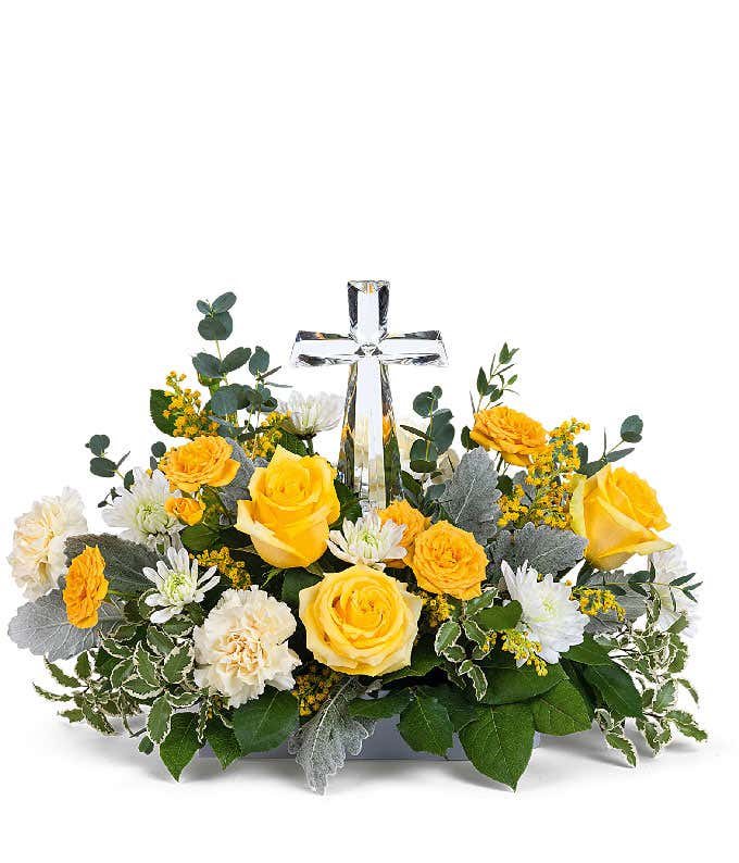 A stunning arrangement featuring yellow roses (deluxe & premium only), yellow spray roses, light yellow carnations, white mums, yellow solidago, and floral greens, elegantly accented with a crystal cross. This vibrant mix offers a bright and uplifting dis