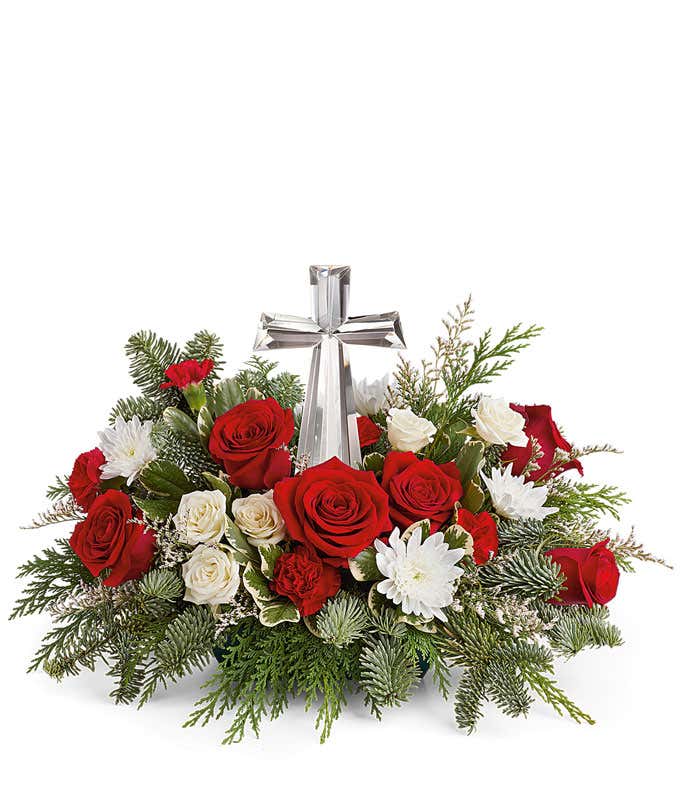 A beautiful arrangement with red roses, white spray roses, white cushion chrysanthemums, floral greens, and a keepsake crystal cross.